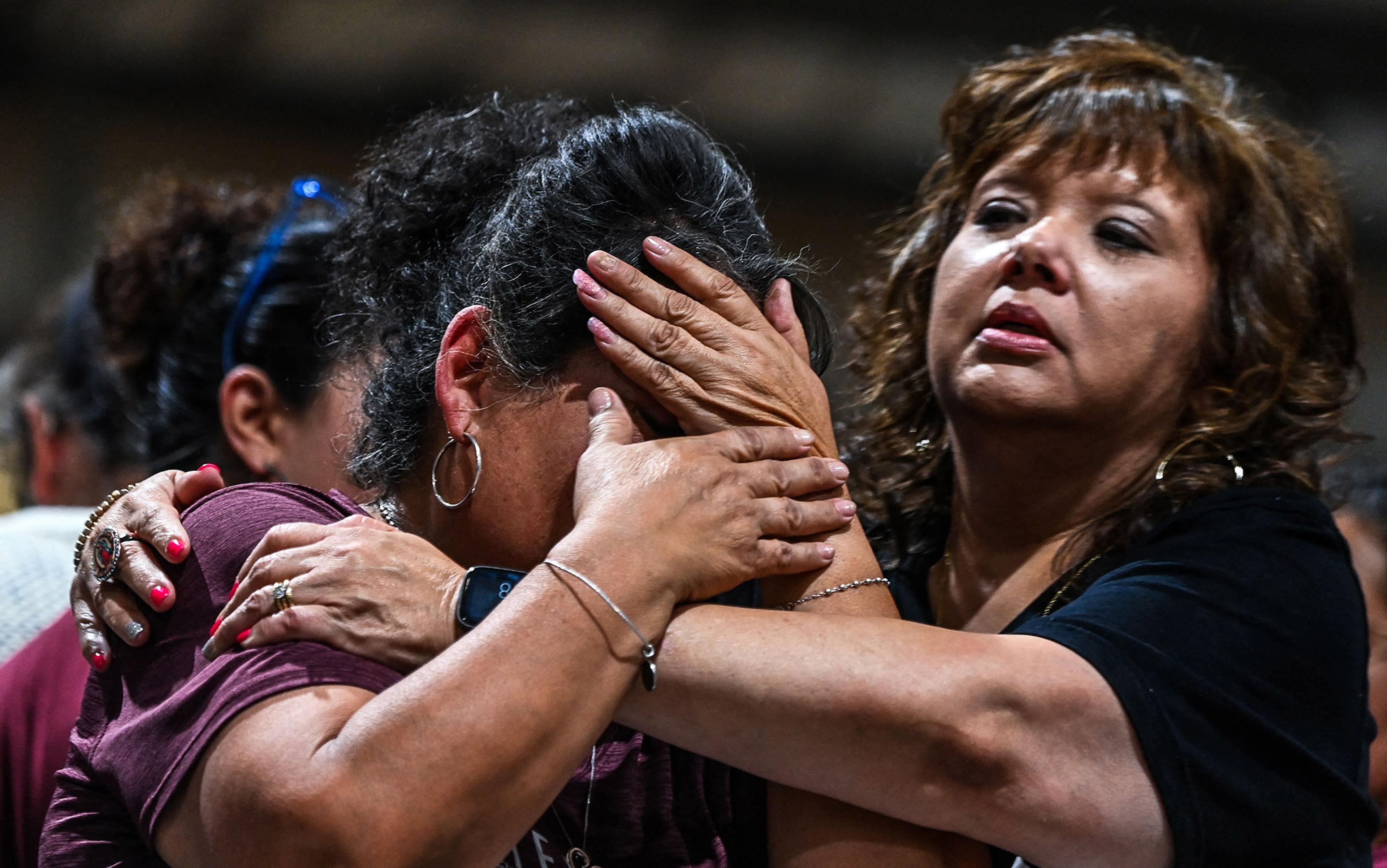 A close-up shot of one woman holding and comforting another grief-stricken woman